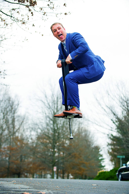 Russell Heimlich on a pogo stick in a suit